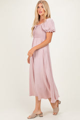 woman wearing a mauve puff sleeve midi dress with a smocked bodice and flowing skirt