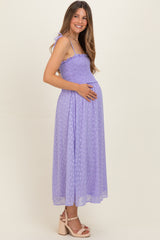 woman wearing a lavender maternity dress with smocking detail and a baby bump, standing sideways