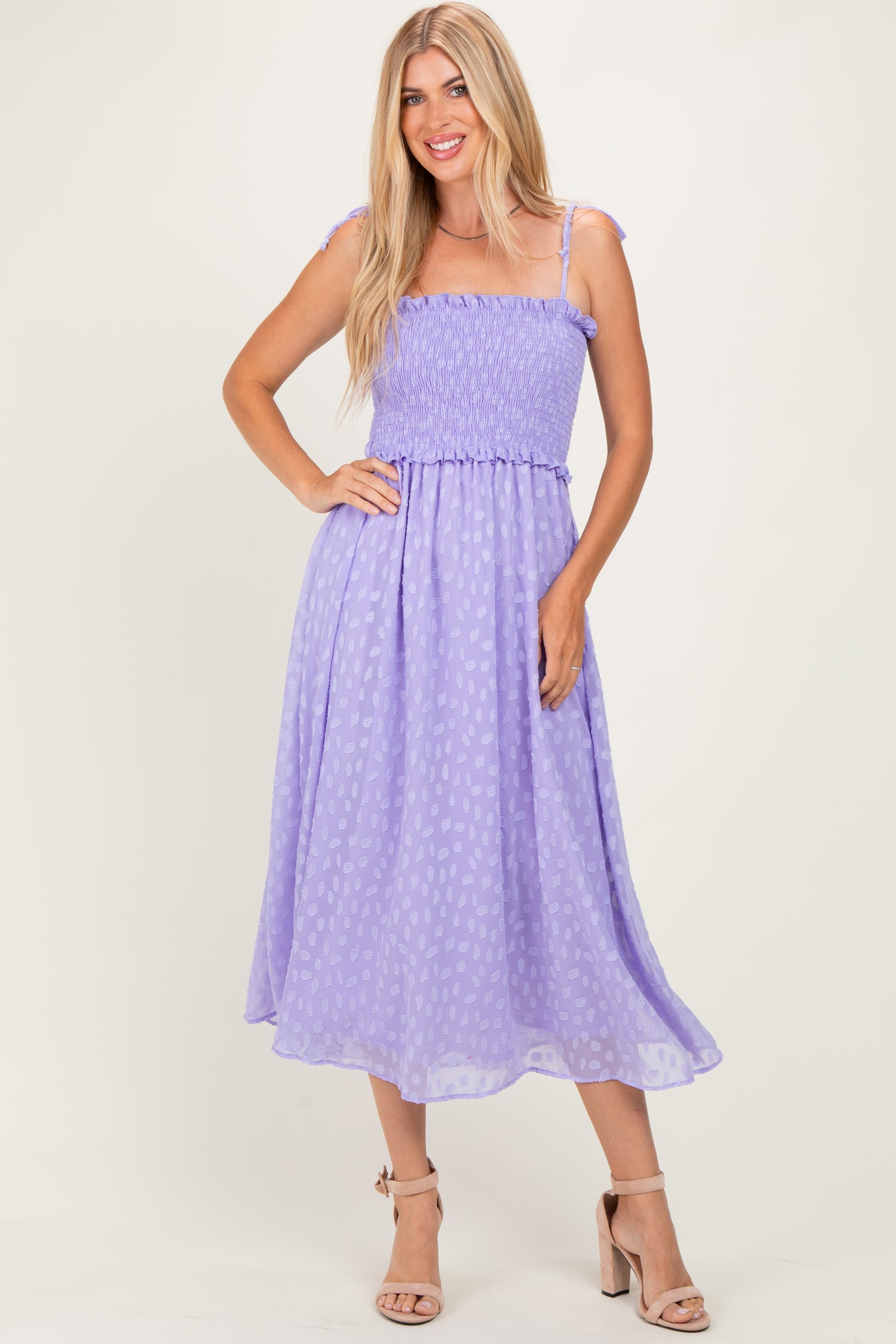 woman wearing a light purple, smocked sundress with shoulder ties and a flowy skirt