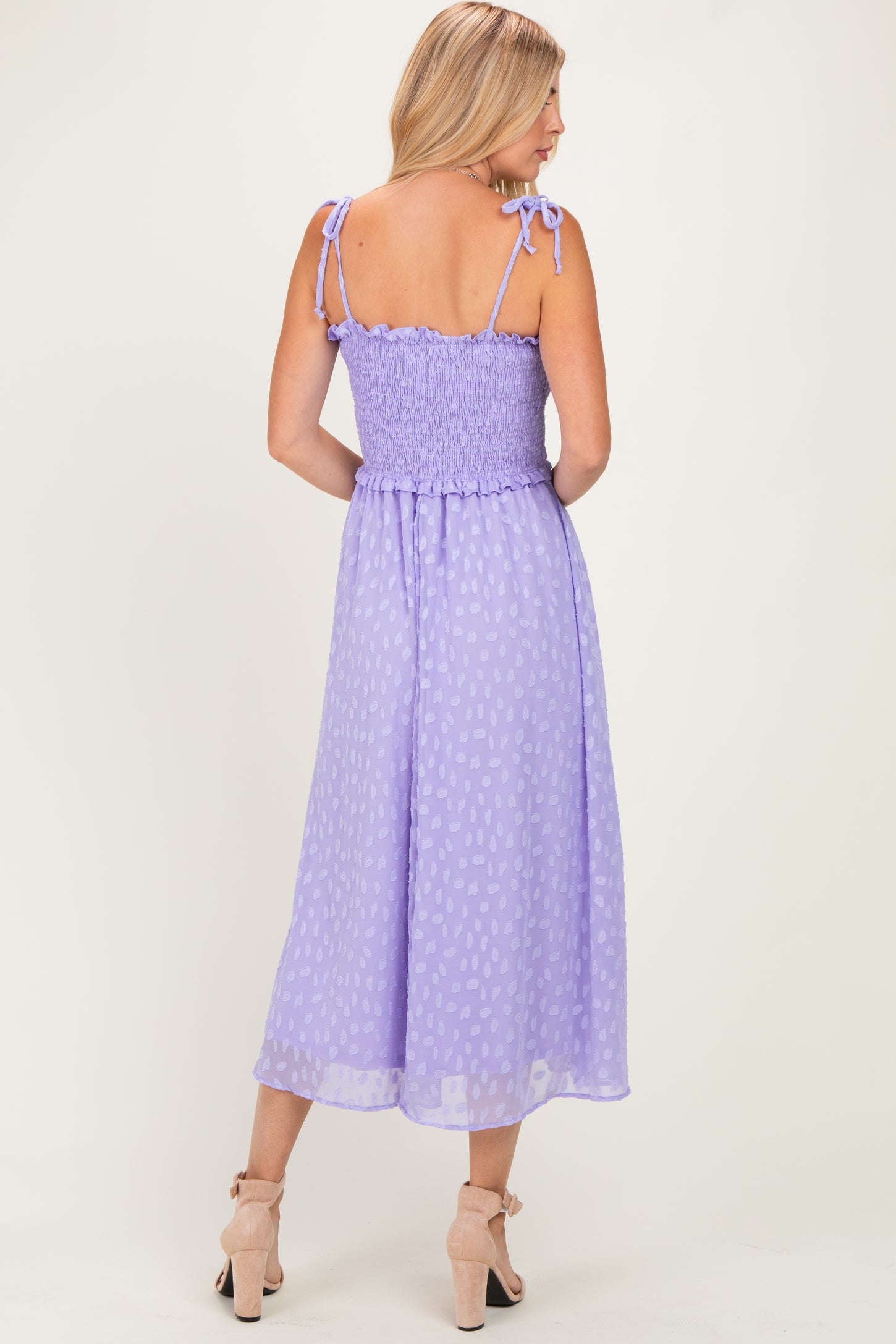 woman wearing a lavender midi dress with smocked bodice and tie straps, viewed from the back