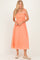 woman wearing a coral midi sundress with a smocked bodice and adjustable shoulder straps