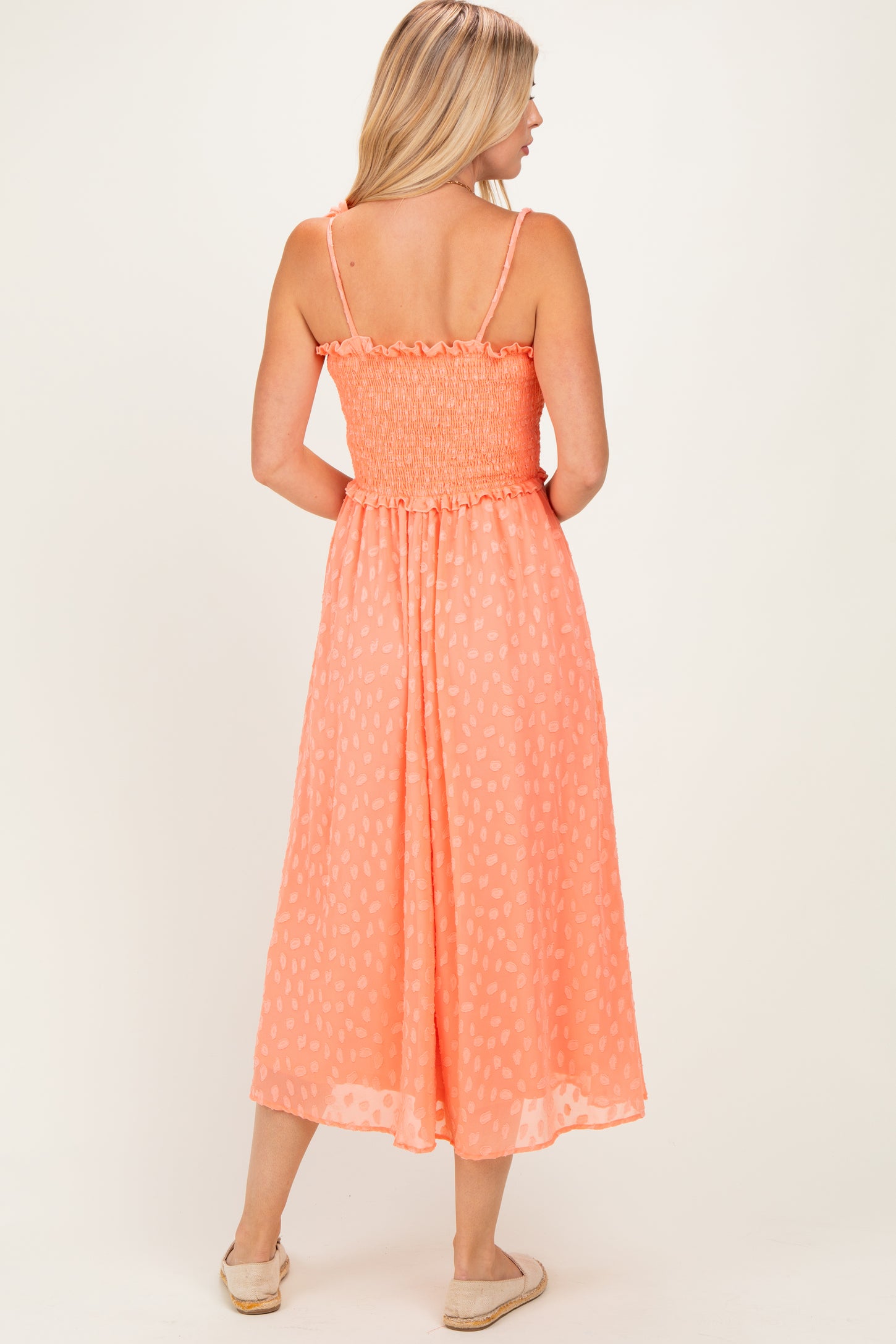 woman wearing a coral smocked back maxi dress with spaghetti straps and a flowy skirt