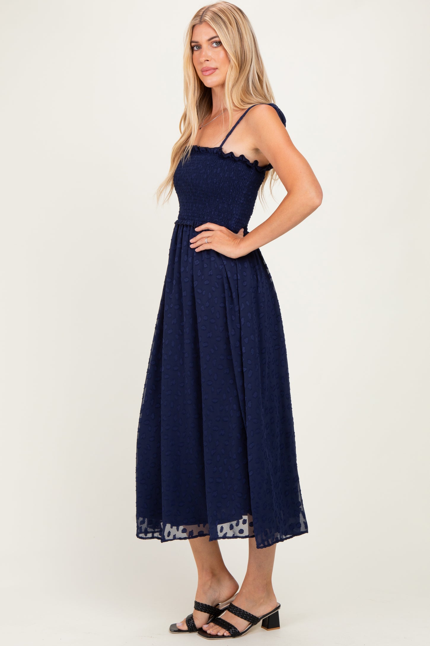 woman wearing a navy blue smocked maxi dress with ruffled straps and a flowy skirt