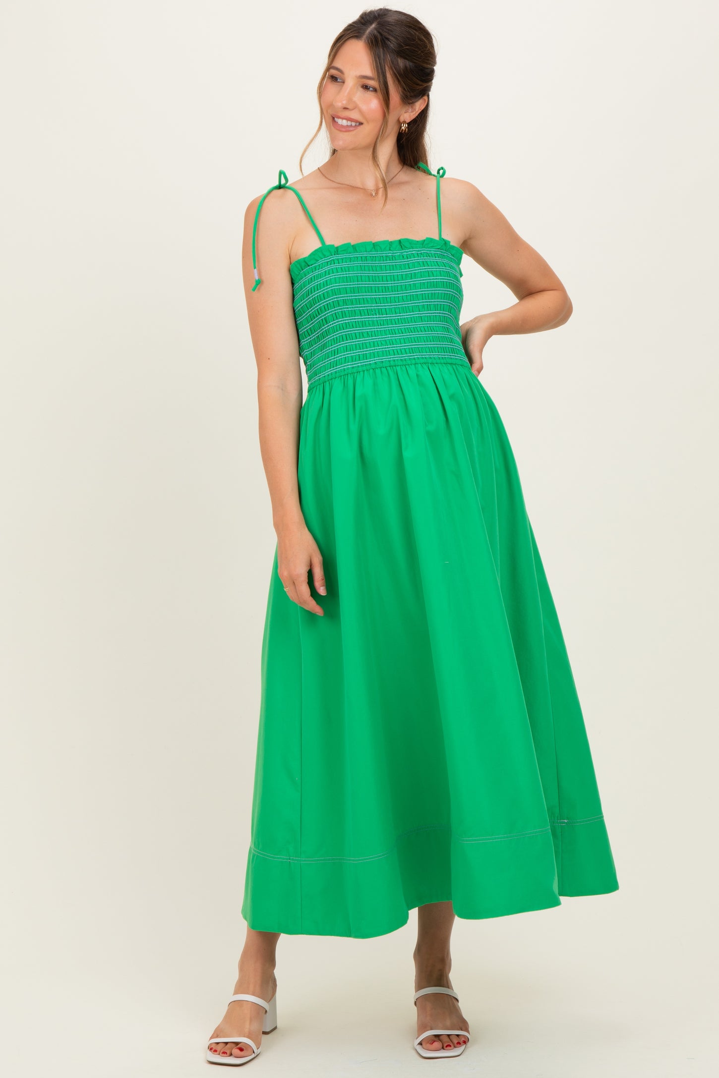 woman wearing a bright green maternity dress with a smocked bodice and adjustable straps