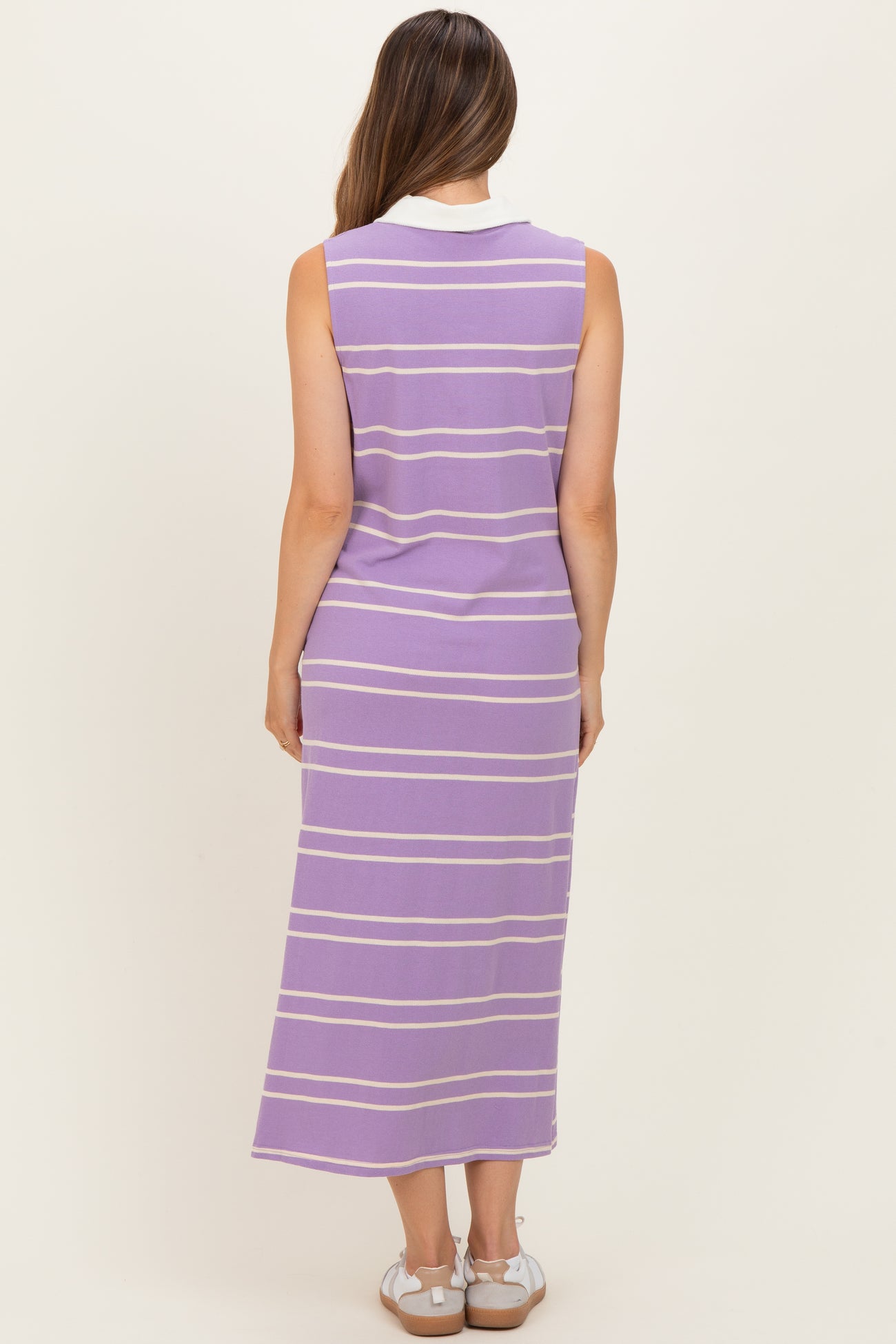 woman wearing a purple striped sleeveless maternity dress, showing a relaxed fit and ankle-length design from the back