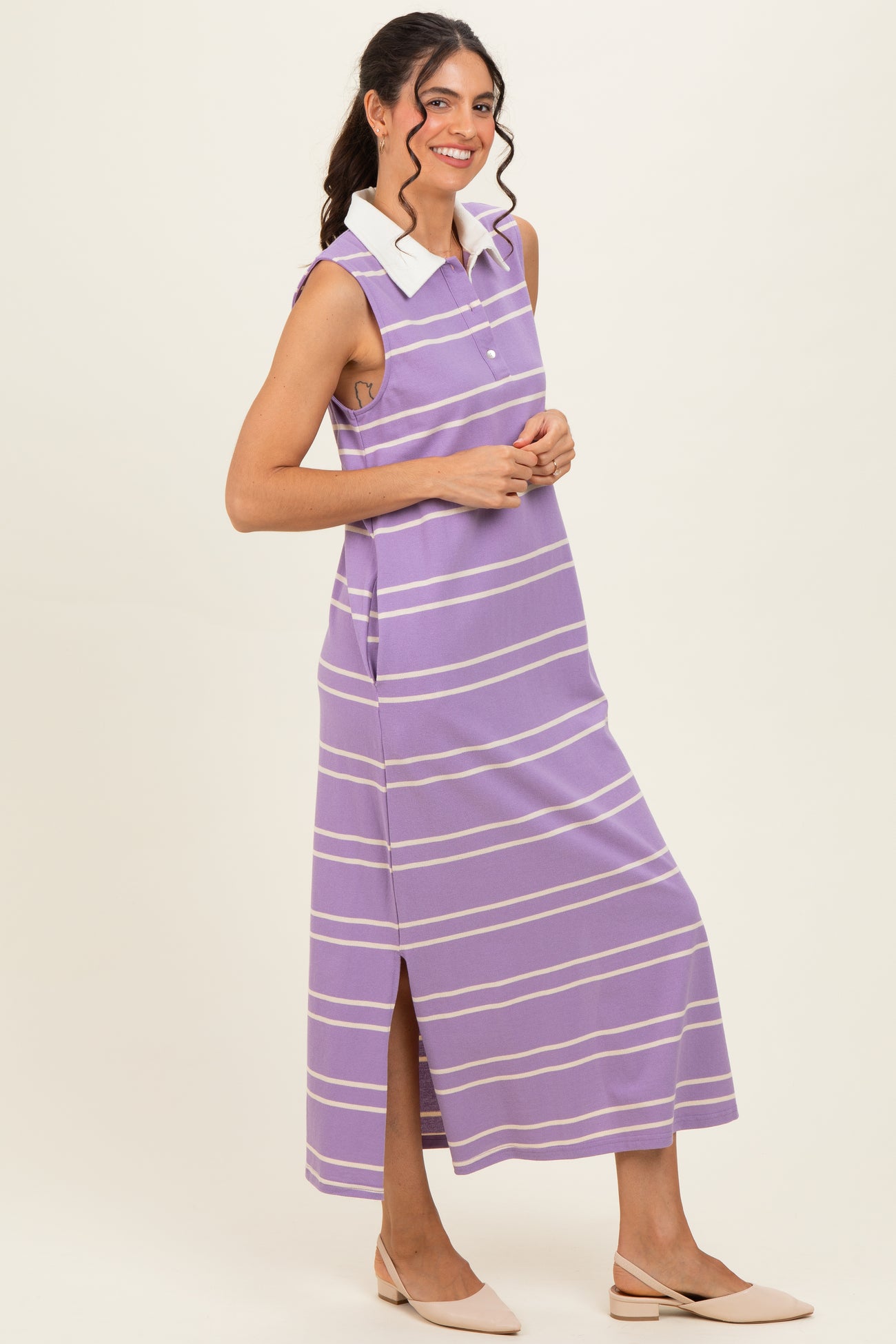 woman wearing a purple striped sleeveless maxi dress with a white collar and side slits