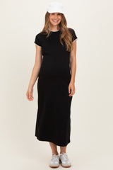woman wearing a black maternity dress with short sleeves and white trim, standing and showing her baby bump