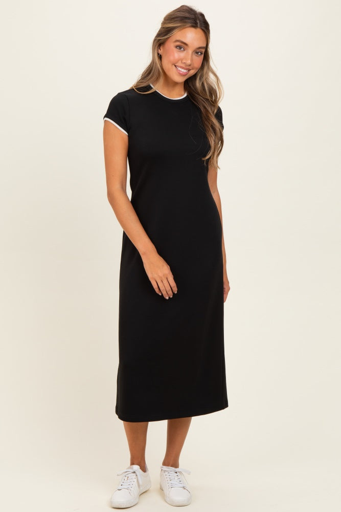 woman wearing a black short sleeve midi dress with white trim and white sneakers