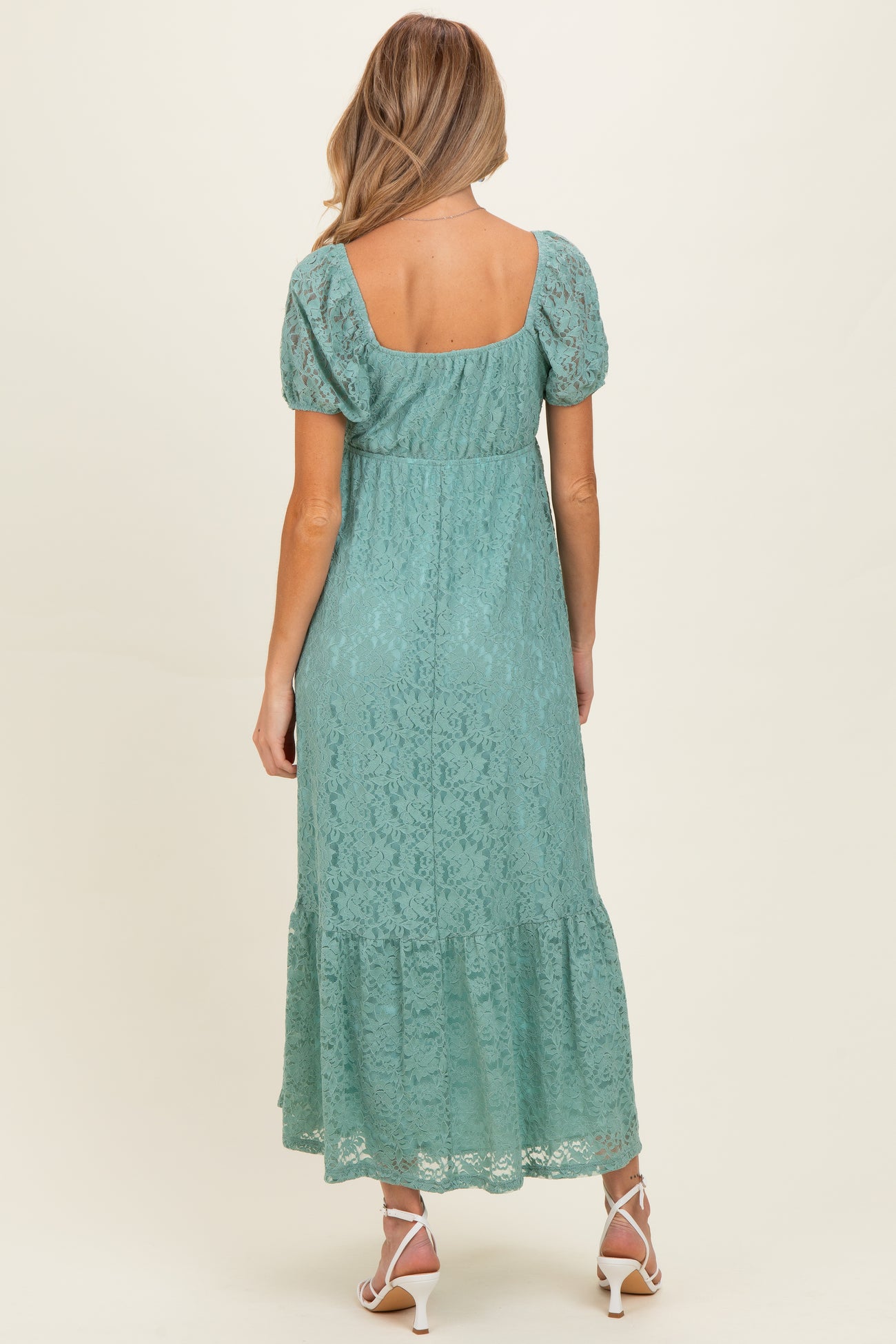 woman wearing a mint green lace maternity maxi dress with short sleeves and a tiered hemline