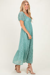 woman wearing a teal lace maxi dress with puff sleeves and a tiered hemline, standing in profile