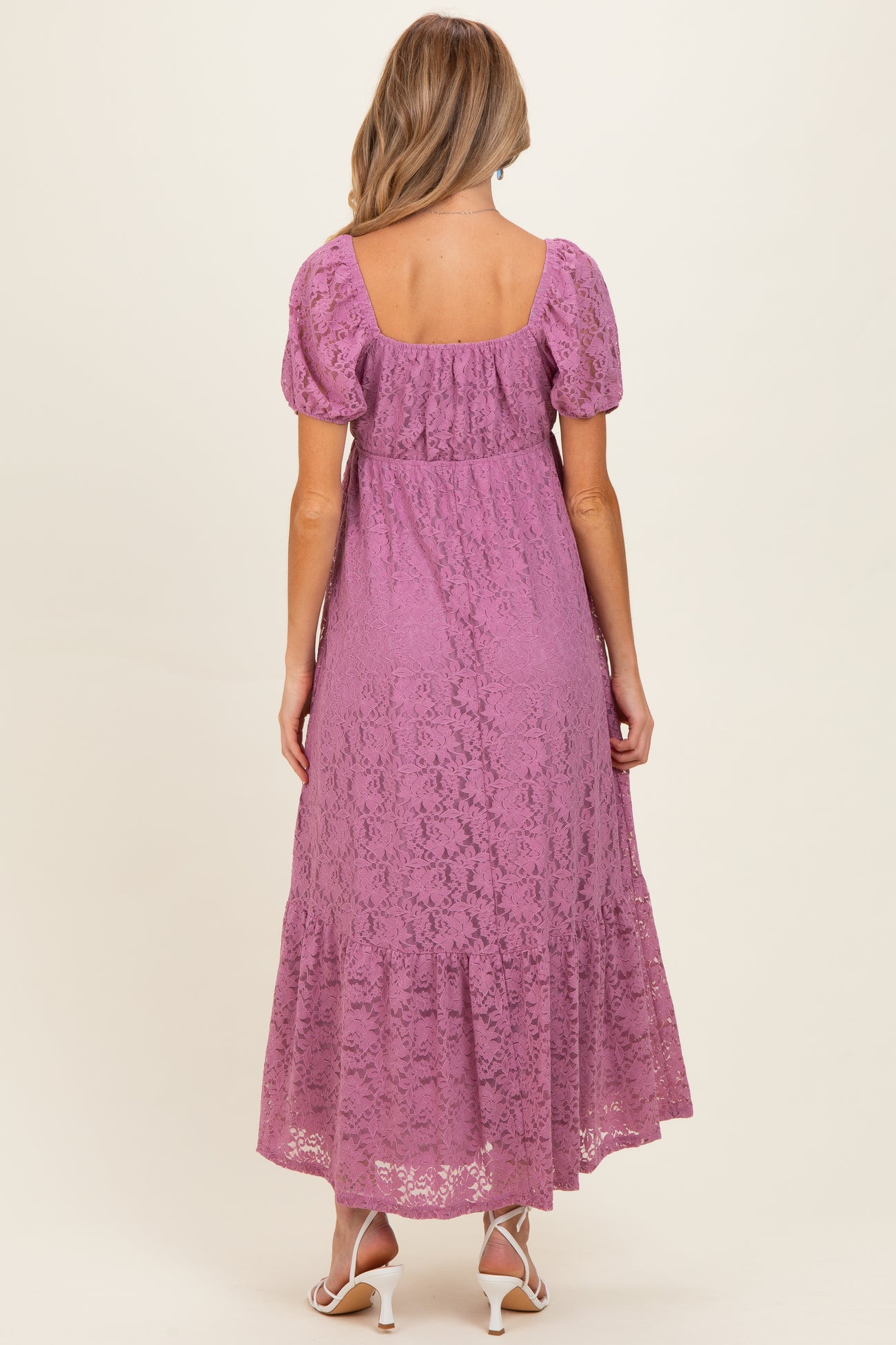 woman wearing a lavender lace maternity maxi dress with short puff sleeves and a tiered hem, showing a baby bump