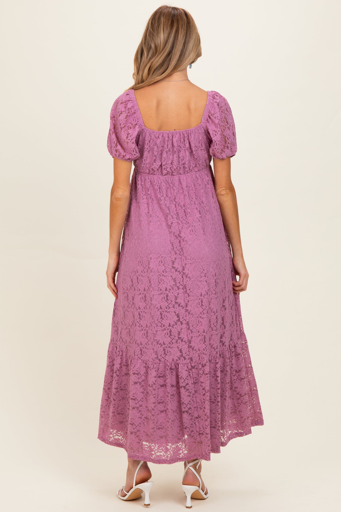 woman wearing a lavender lace maternity maxi dress with short puff sleeves and a tiered hem, showing a baby bump