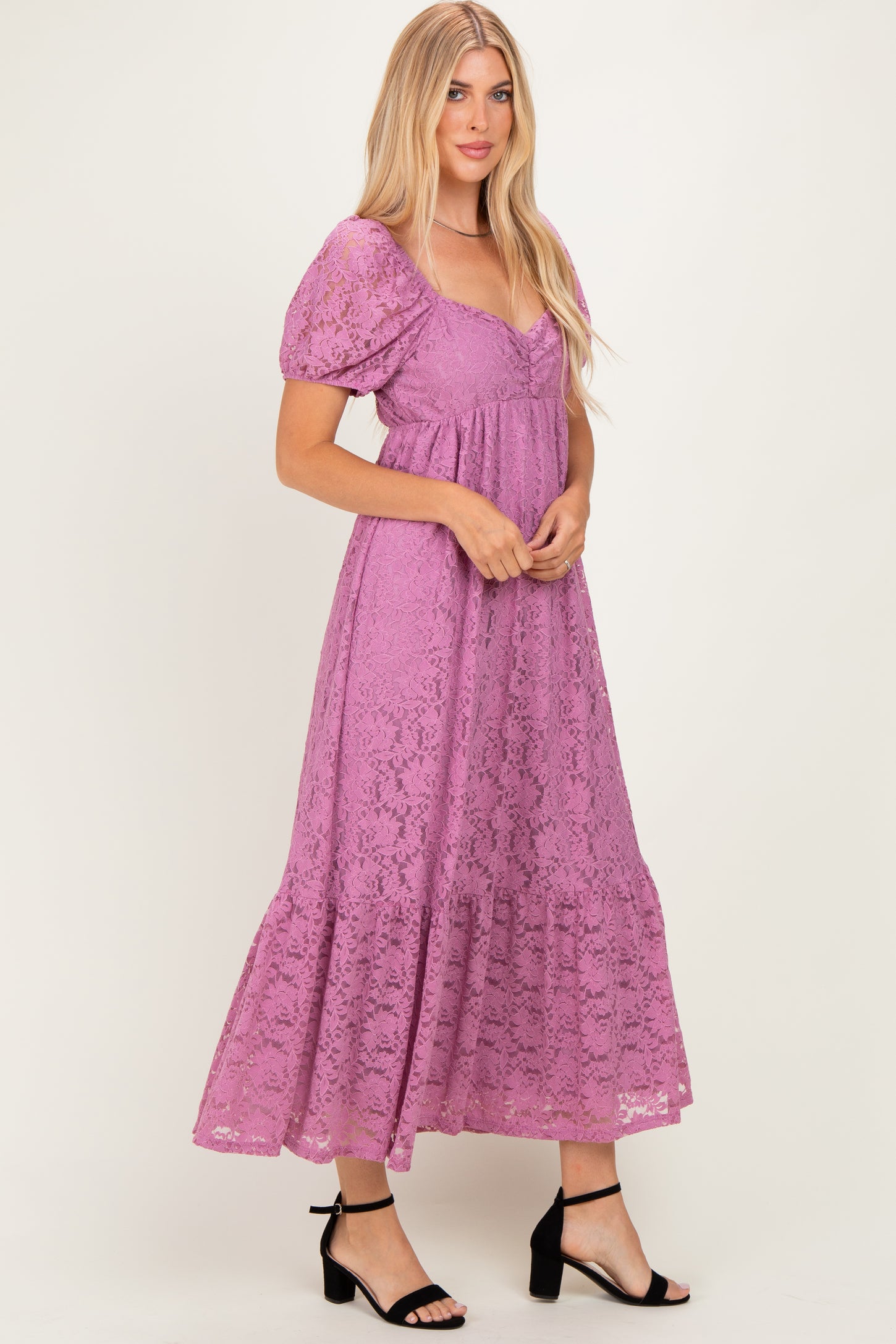 woman wearing a purple lace maxi dress with puff sleeves and a tiered skirt, standing in a relaxed pose