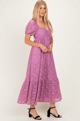 woman wearing a purple lace maxi dress with puff sleeves and a tiered skirt, standing in a relaxed pose
