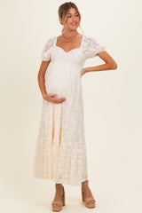woman wearing a cream lace maternity maxi dress with short puff sleeves and holding her baby bump