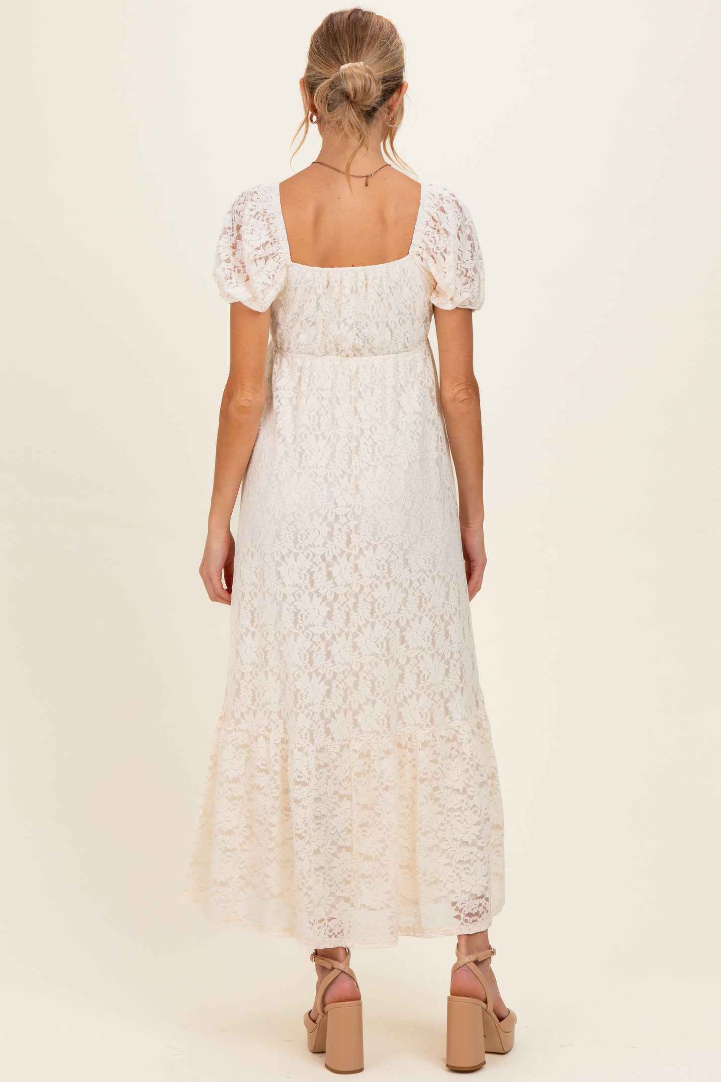 woman wearing a white lace maternity dress with puff sleeves, shown from the back