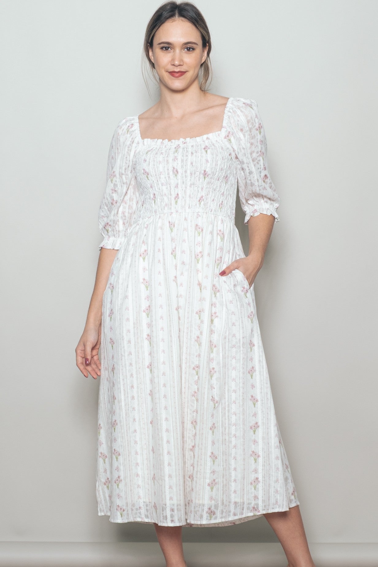 woman wearing a white floral print midi dress with puff sleeves and pockets