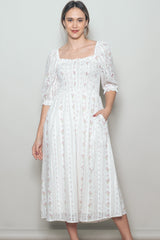 woman wearing a white floral print midi dress with puff sleeves and pockets
