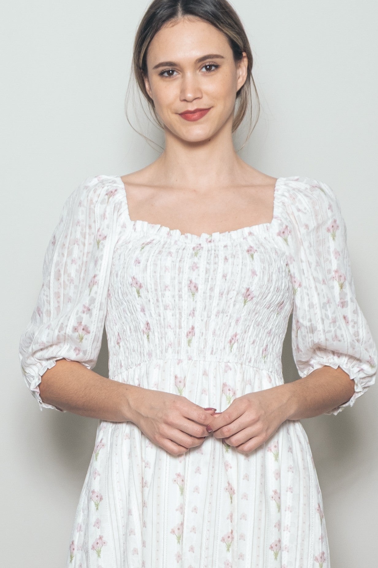 woman wearing a white floral smocked dress with puff sleeves and a square neckline