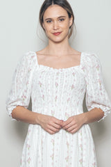 woman wearing a white floral smocked dress with puff sleeves and a square neckline