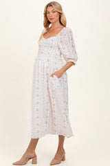 woman wearing a white floral print maternity dress with puff sleeves and pockets