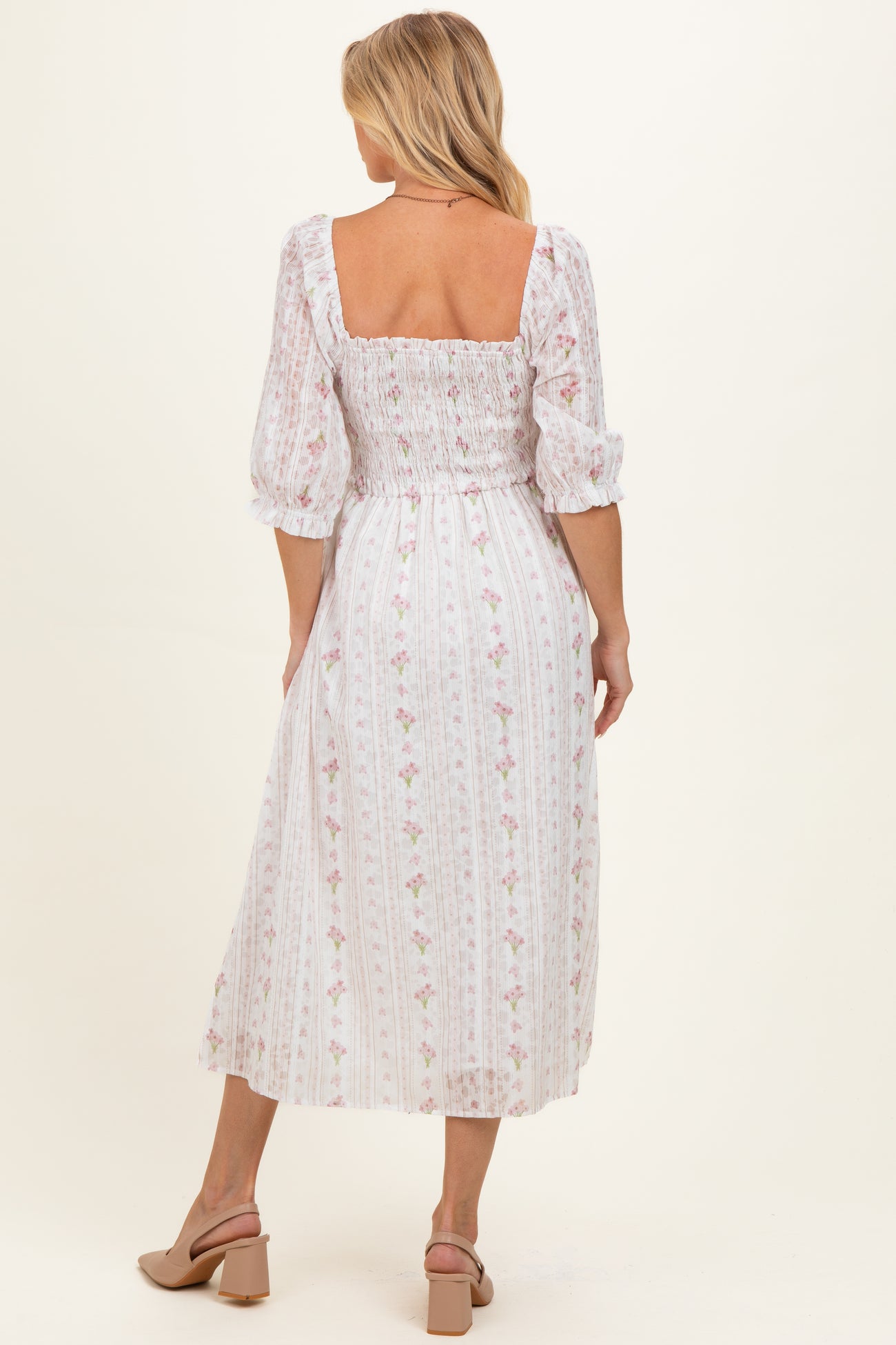 woman wearing a white floral print maternity dress with smocked bodice and puff sleeves, baby bump visible