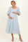 woman wearing a light blue floral maternity dress with a square neckline and puff sleeves, cradling her baby bump
