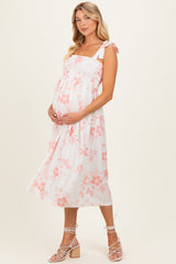 woman wearing a floral print maternity maxi dress with a smocked bodice and tie straps, showcasing her baby bump