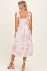woman wearing a white floral maternity dress with a smocked bodice and tied straps, showing her back