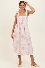 woman wearing a white floral print midi dress with pink flowers and shoulder ties