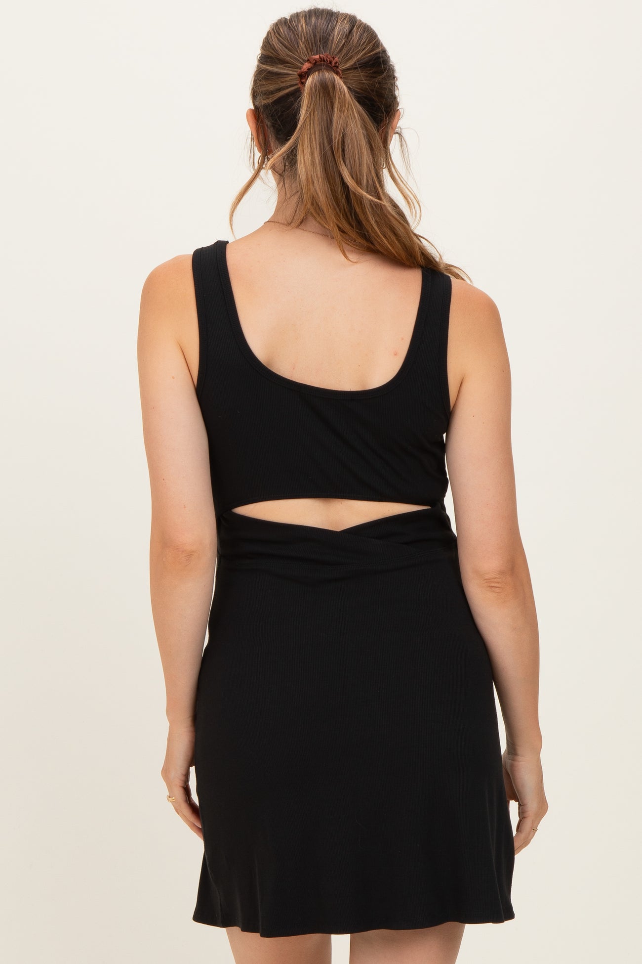 woman wearing a black maternity dress with a fitted top and cut-out back detail