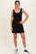 woman wearing a black sleeveless mini dress with a fitted silhouette and black and white sneakers