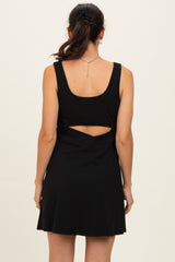 woman wearing a black sleeveless dress with a scoop back and cut-out detail at the waist