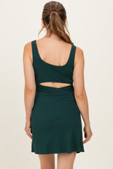 woman wearing a dark green maternity dress with a back cutout and a fitted bodice