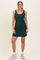 woman wearing a dark green sleeveless ribbed dress with a fitted silhouette and casual sneakers