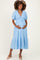 woman wearing a light blue maternity dress with puff sleeves and a tiered skirt, gently cradling her baby bump
