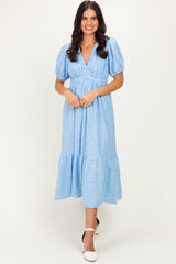woman wearing a light blue midi dress with puff sleeves and a tiered hem