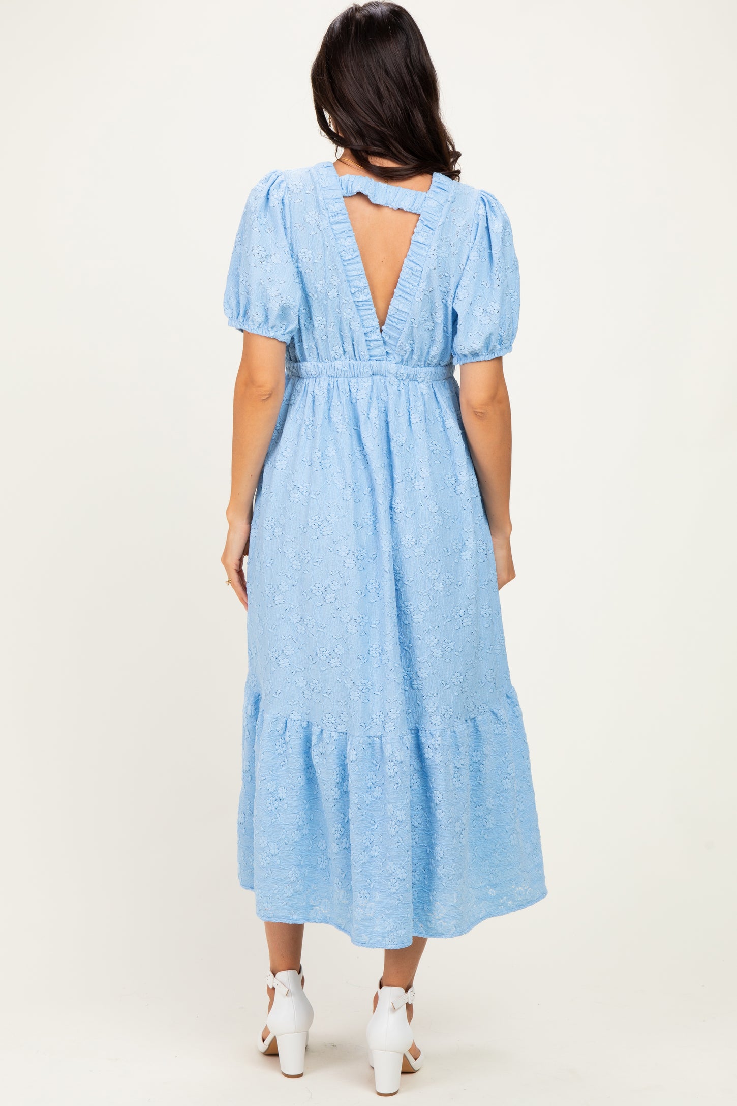 woman wearing a light blue lace midi dress with puff sleeves and a back cutout detail