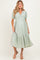 woman wearing a light green short sleeve maternity dress with a v-neck and tiered skirt, showcasing her baby bump