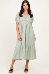 woman wearing a light green puff sleeve midi dress with a v-neck and tiered skirt, standing against a neutral background