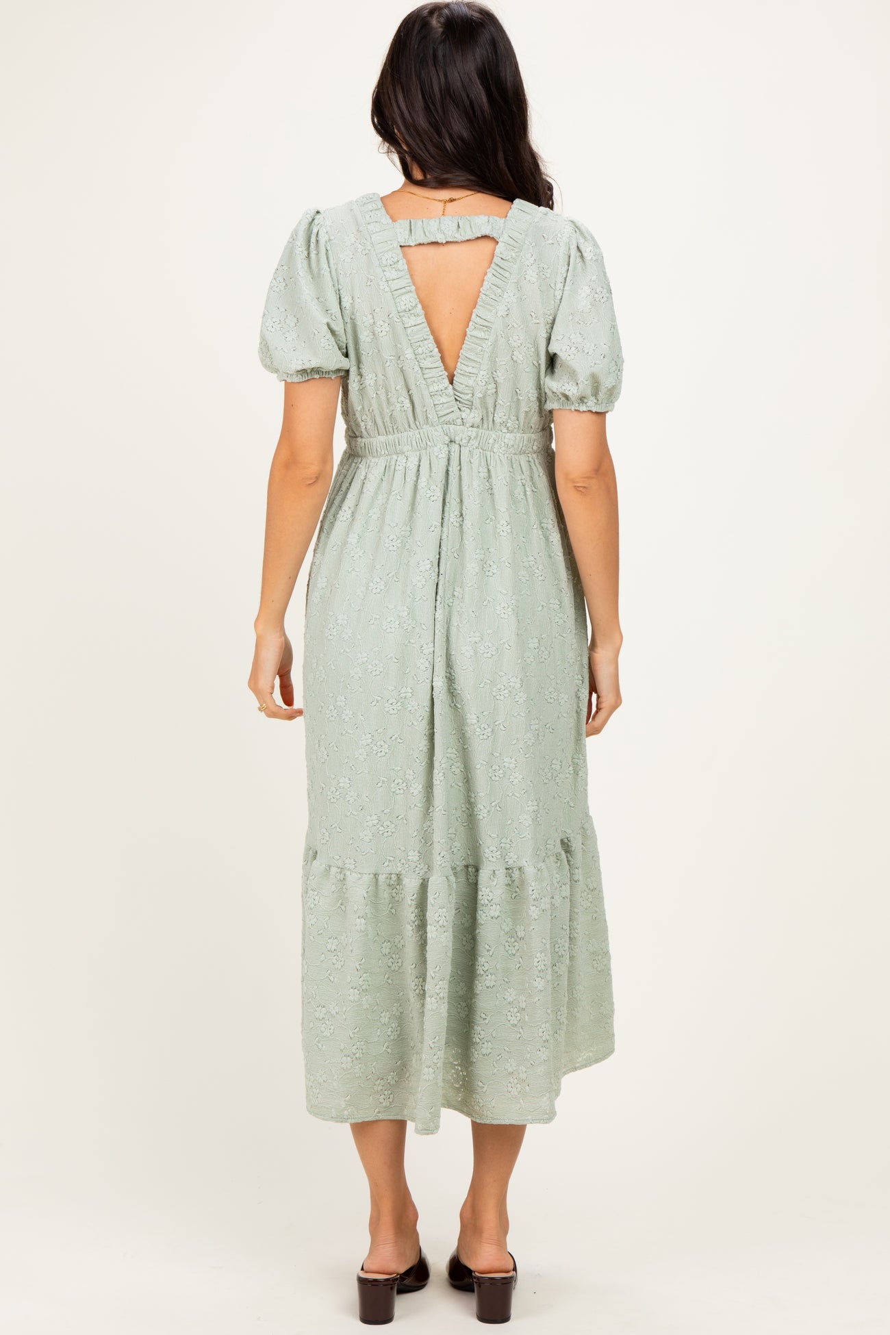 woman wearing a light green floral midi dress with short puff sleeves and a keyhole back detail