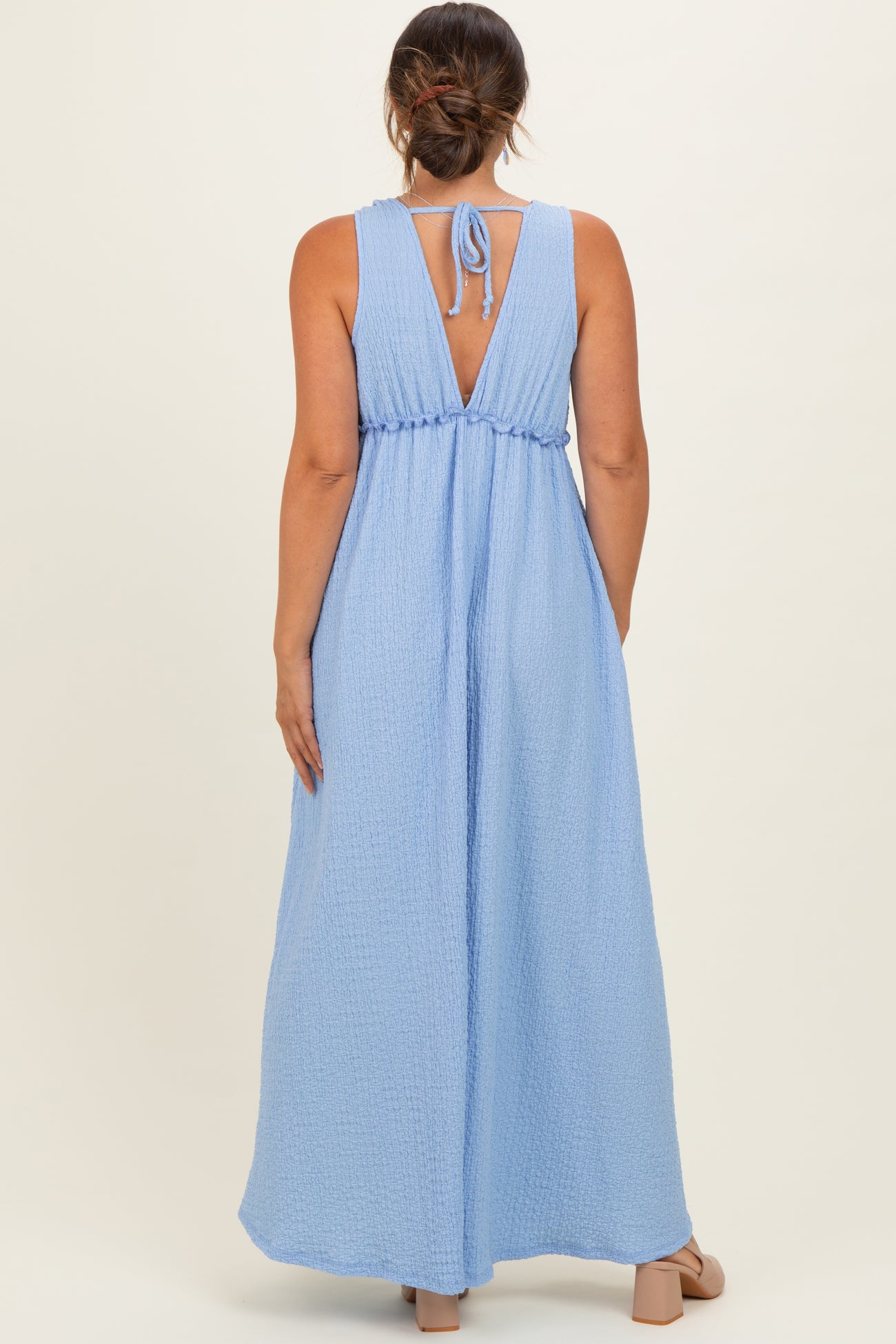 woman wearing a light blue maternity maxi dress with a tie-back detail and a smocked waist