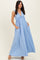 woman wearing a light blue sleeveless maxi dress with a v-neck and side pockets