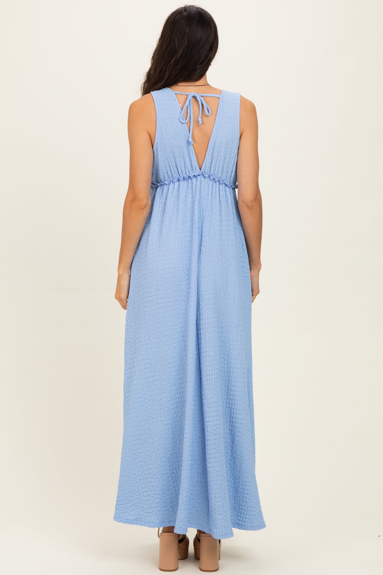 woman wearing a light blue maxi dress with a tie-back detail and a loose fit from the back view