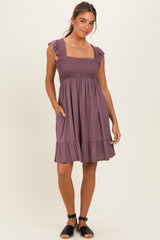 woman wearing a lavender smocked sundress with ruffled straps and pockets, standing on a light background