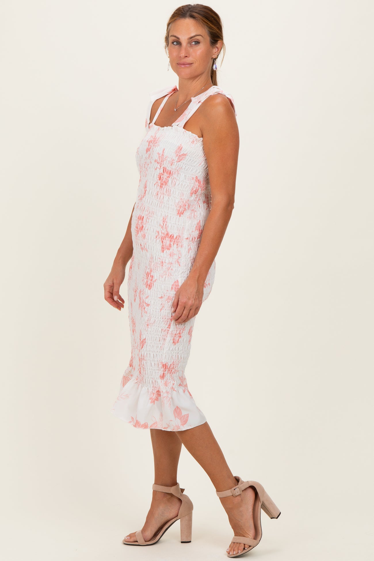 woman wearing a white and pink floral smocked midi dress with ruffled hem and spaghetti straps