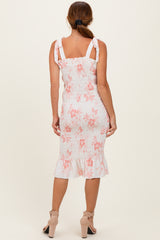 woman wearing a white floral smocked midi dress with pink flowers and ruffled hem, showing the back view