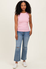 woman wearing a light pink ribbed tank top and distressed flared jeans with white sneakers