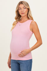woman wearing a light pink maternity tank top and gently cradling her baby bump