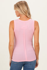 woman wearing a light pink sleeveless maternity top with a back detail and fitted style